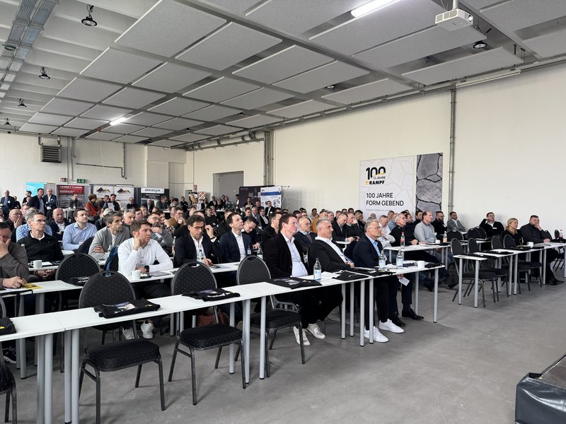 Großes Publikum bei einer Konferenz zur Betonindustrie mit Banner „100 Jahre Knauf Formgebend“ im Hintergrund